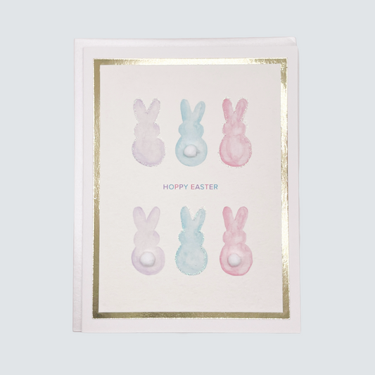 Handmade Easter card with watercolor bunny designs, pom-poms, and gold foil border, blank inside.