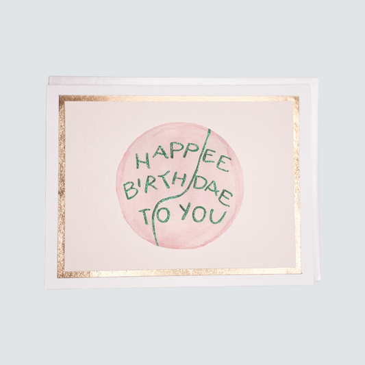 Flat handmade “Happee Birthdae” card with pink and green lettering, rose gold foil border, blank inside.