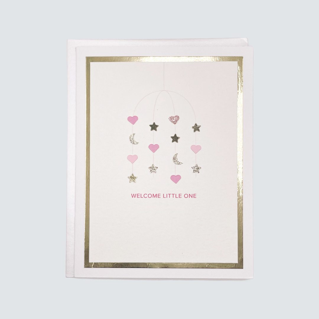 Handmade pink baby card with watercolor mobile design and gold foil accents, blank inside on white cardstock.