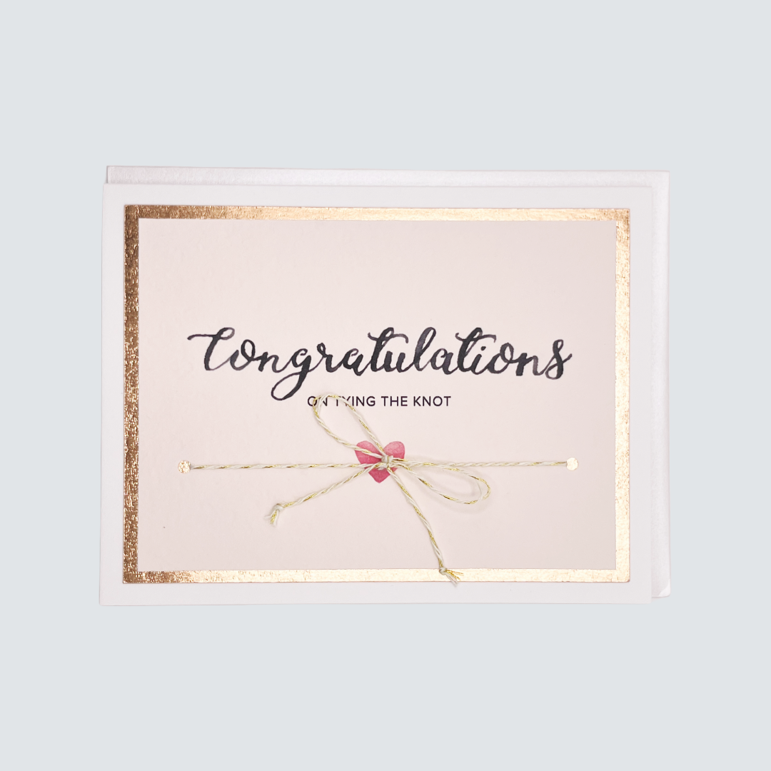 Handmade wedding card with “Tying the Knot” message, rose gold foil border, and twine embellishment, blank inside.