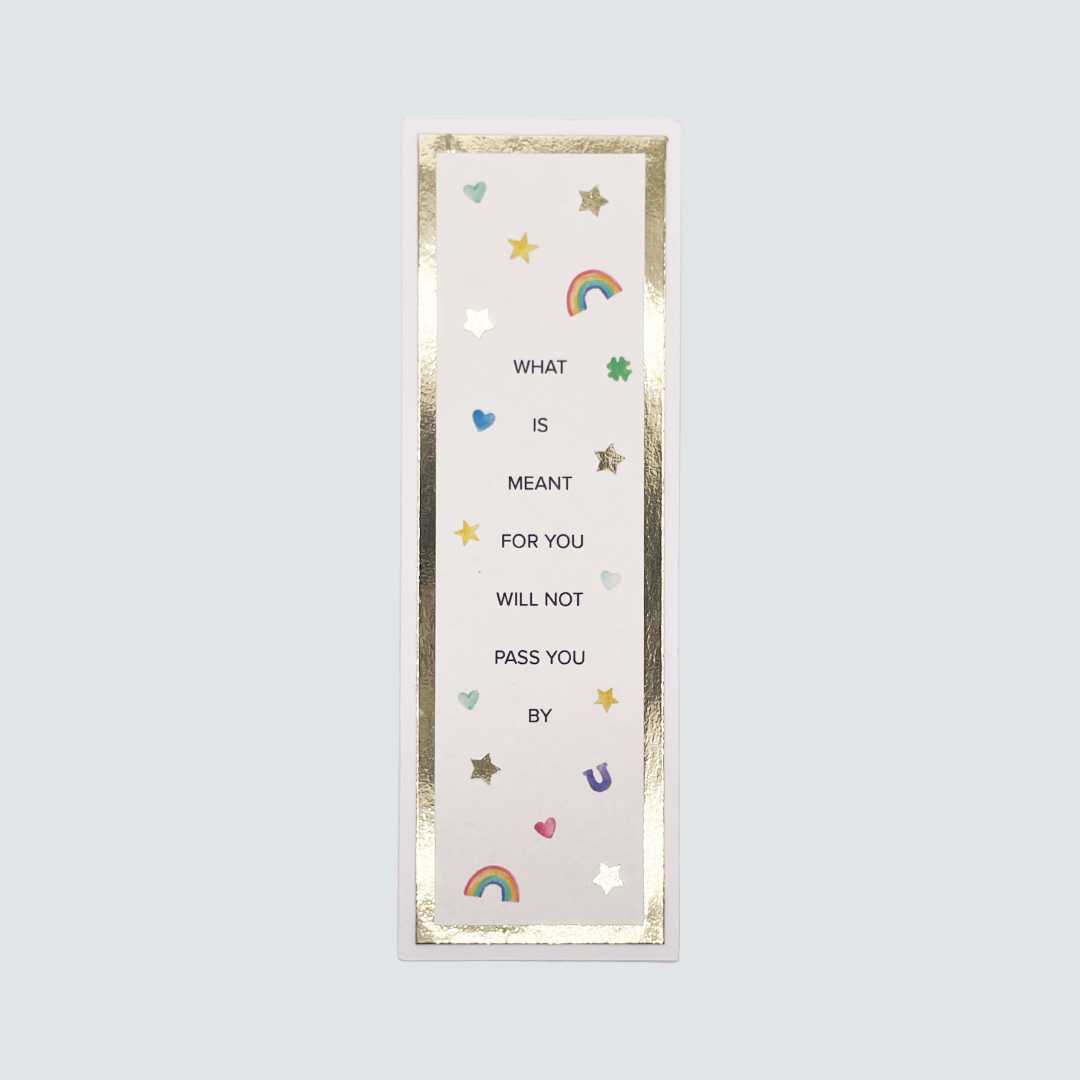 A bookmark with a white background featuring gold foil cardstock, stars, and the text 'What is meant for you will not pass you by' along with a rainbow and hearts illustration.