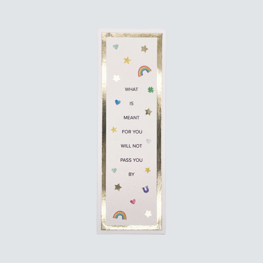 A bookmark with a white background featuring gold foil cardstock, stars, and the text 'What is meant for you will not pass you by' along with a rainbow and hearts illustration.