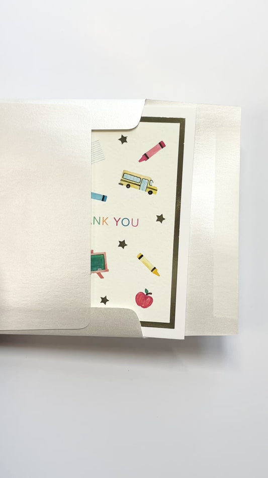 Person opening a handmade teacher thank you card with watercolor artwork and gold foil accents from a white envelope.