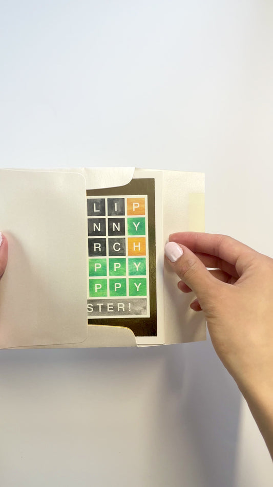 Hands opening an envelope to reveal a handmade Wordle-style Easter card with gold foil accents.