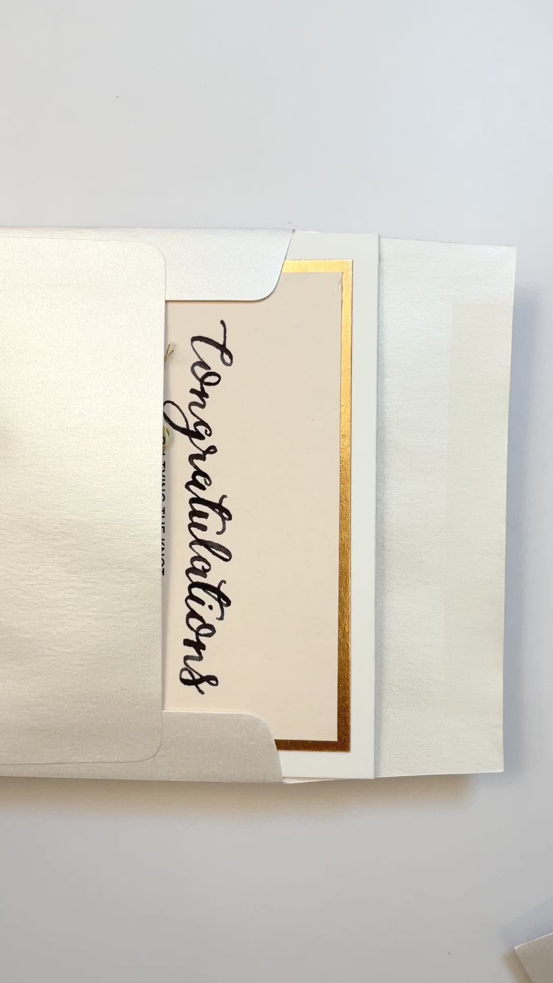 Hands opening an envelope to reveal a handmade “Tying the Knot” wedding card with rose gold foil and twine.