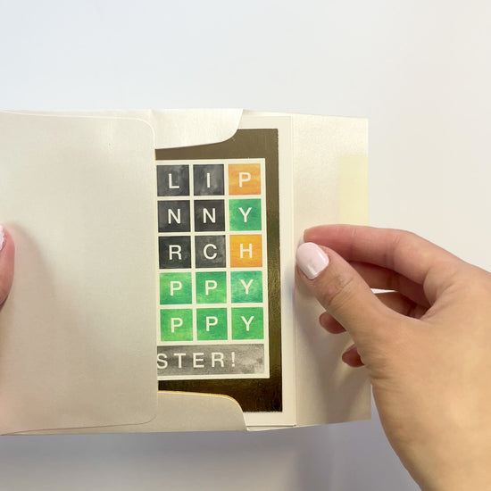 Hands opening an envelope to reveal a handmade Wordle-style Easter card with gold foil accents.