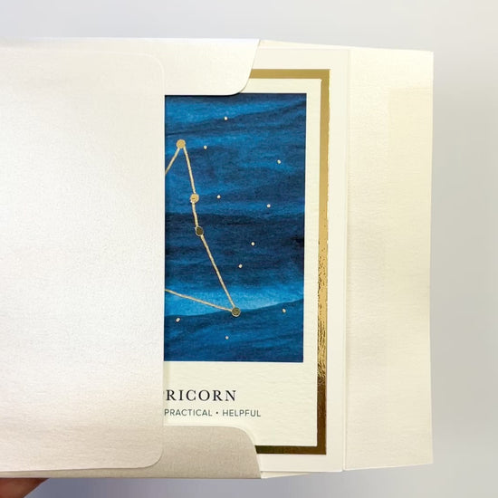 Handmade Capricorn zodiac constellation card with watercolor sky and gold foil accents, blank inside on FSC-certified cardstock.