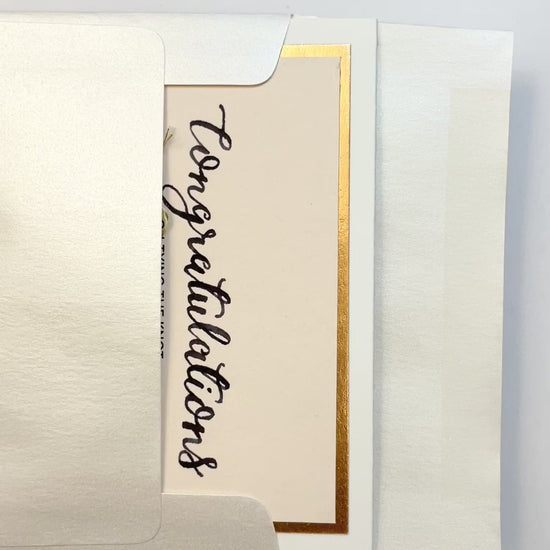 Hands opening an envelope to reveal a handmade “Tying the Knot” wedding card with rose gold foil and twine.