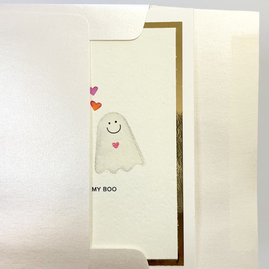 Hands opening an envelope to reveal a handmade “You’re My Boo” card with watercolor ghosts and gold foil.