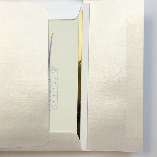 Hands opening an envelope to reveal a handmade funfetti birthday card with gold foil and watercolor sprinkles.